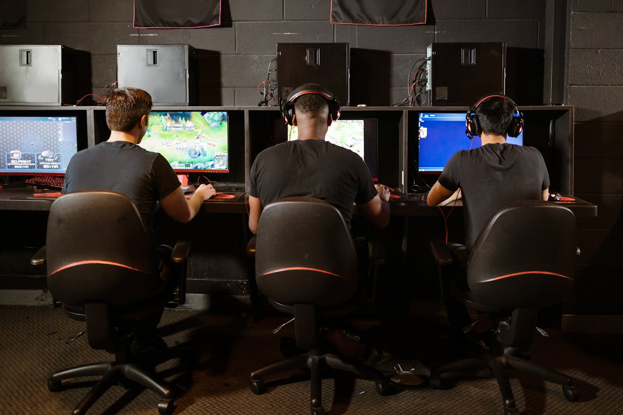 About A group of men intensely focused on playing video games at a modern gaming arcade.