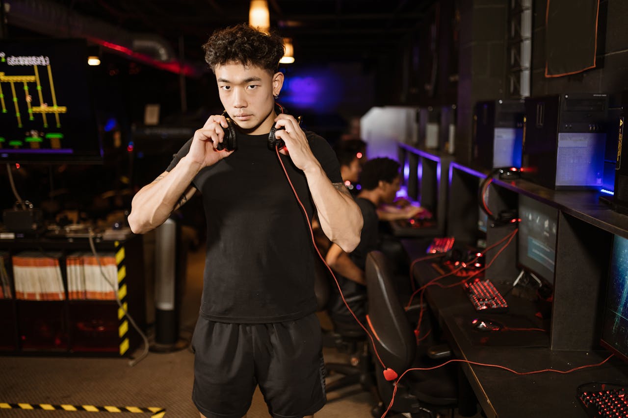 Home A serious young man in a gaming lounge with headphones, embodying the modern e-sports culture.