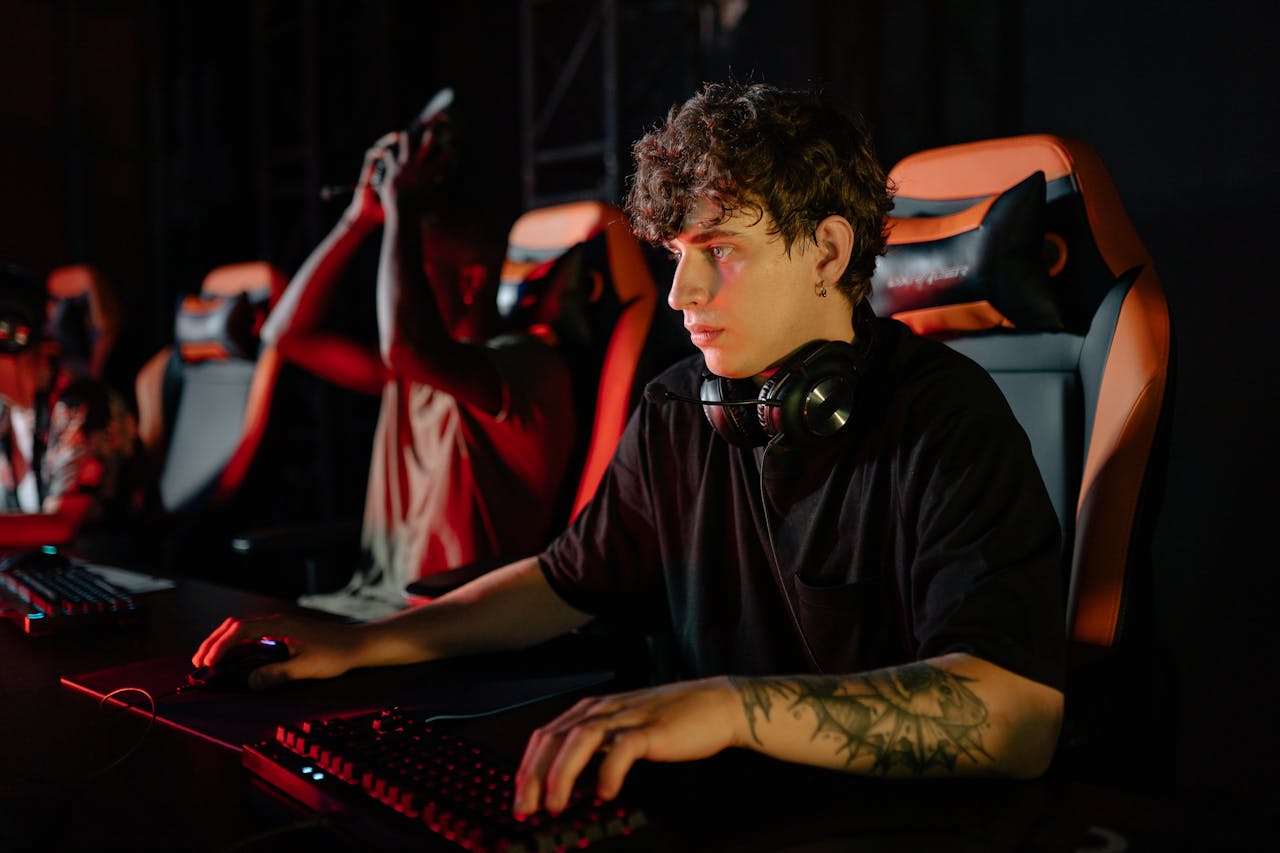 Home Competitive gamers in an esports tournament concentrating deeply in dimly lit setting.